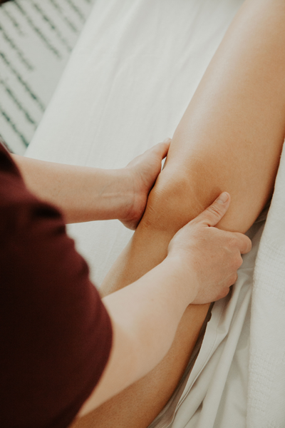 Massage therapist's hands around a knee, gently massaging.